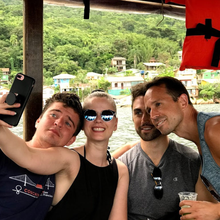 Remote worker community pose for photo on boat in Florianopolis, Brazil