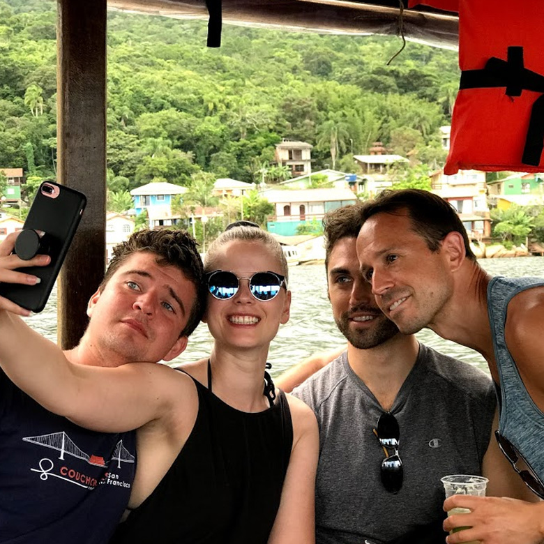 Remote worker community pose for photo on boat in Florianopolis, Brazil