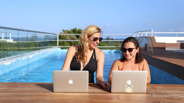 Remote workers on laptops at rooftop pool in Playa del Carmen, Mexico