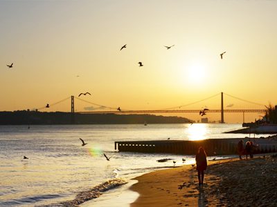 Travelers enjoying the sunrise on the peaceful beach in Lisbon, Portugal