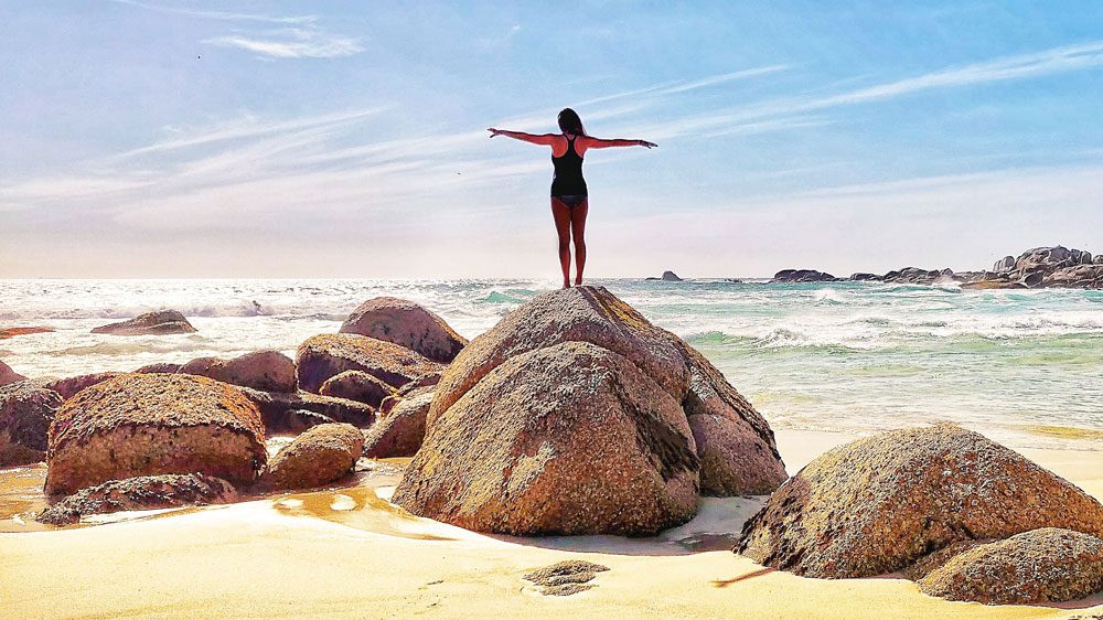 digital nomad standing on a rock staring into the ocean in cape town