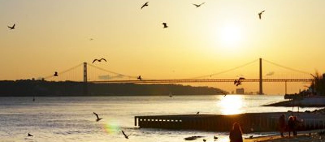 Travelers enjoying the sunrise on the peaceful beach in Lisbon, Portugal