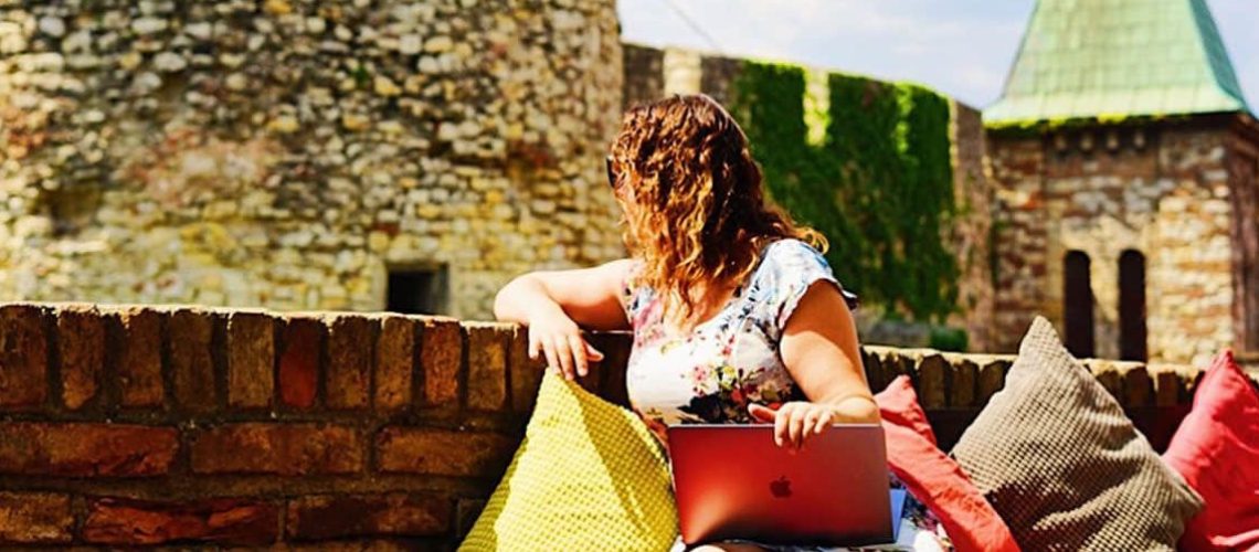 Girl Working on her laptop in Belgrade with a view of a castle in the background