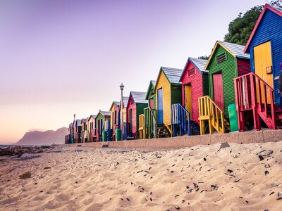 View of the beautiful sunset over False Bay from Kalkbay with little coloured houses on the beach, with mountains in the background, Cape Town, South Africa