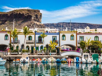 Port In Puerto de Mogan, Gran Canaria, Spain Traditional Colorful Buildings With Boats In Front And Mountain In The Backsground - Puerto de Mogan, Gran Canaria, Canary Islands, Spain